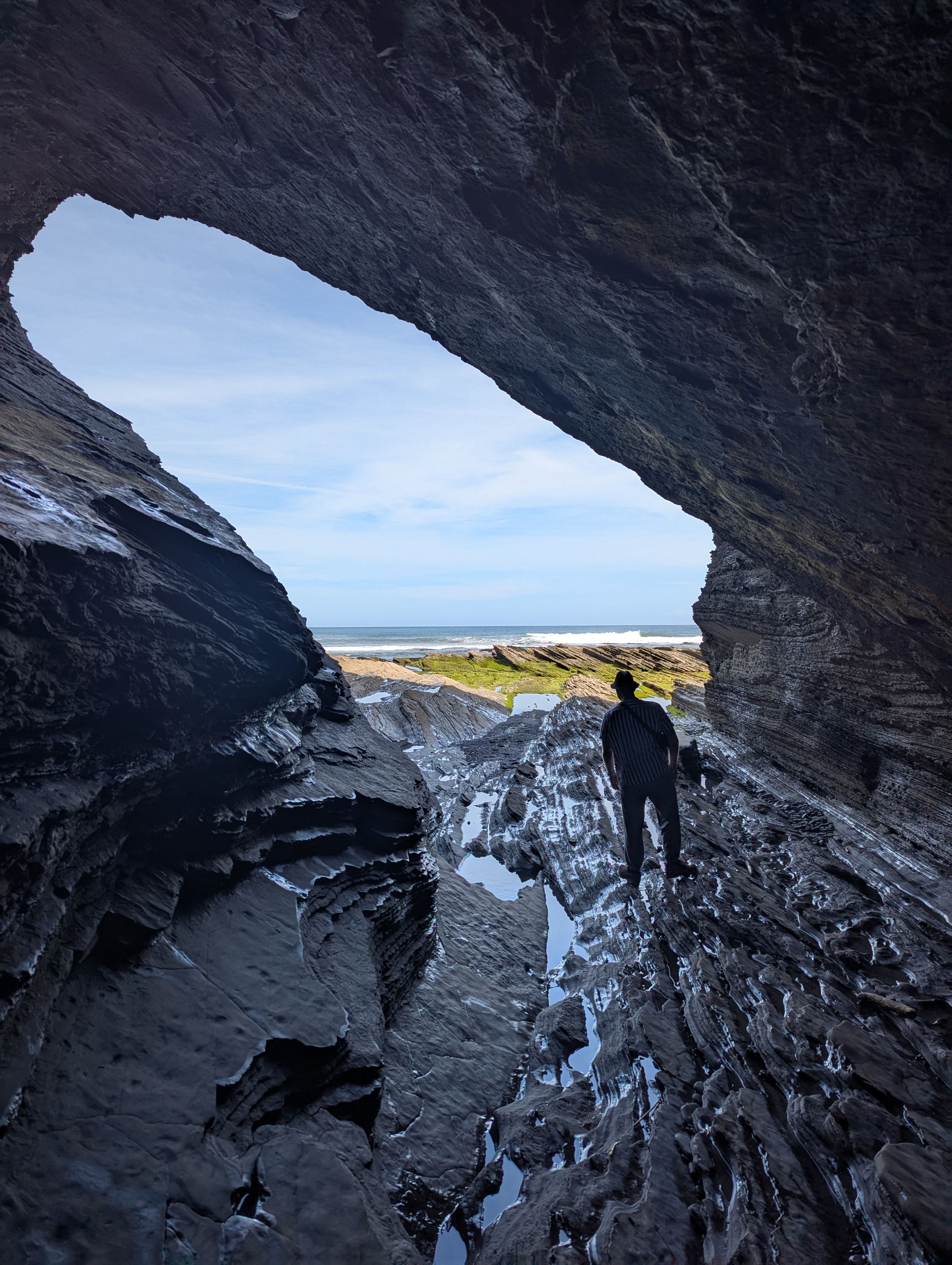 A person in a cave from which you can see the sea